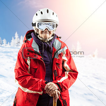 Senior woman in ski jacket and goggles outdoors. With path.