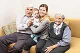 Four generation family sitting on sofa at home