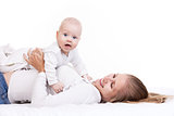Smiling young woman holding baby son while lying on back