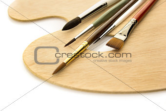 Art brushes on wooden palette isolated
