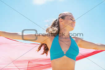 Happy young woman with parero rejoicing on beach