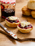 Two scones prepared with clotted cream and jam