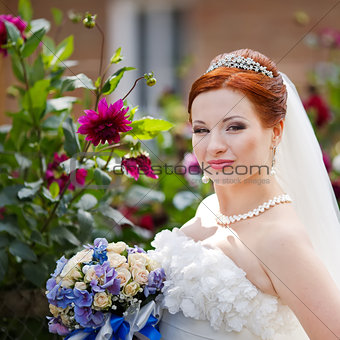 Young bride posing wigh flowers outside.