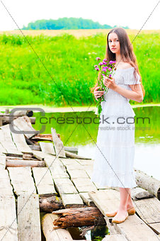 girl on an old wooden bridge with a bouquet of flowers