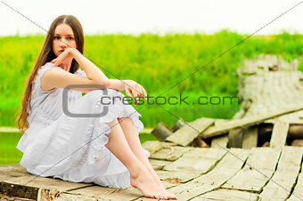 girl in a white sundress resting on the bridge