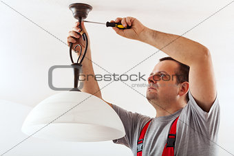 Electrician mounting ceiling lamp