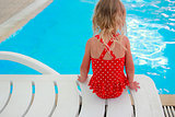 little girl sitting near the pool