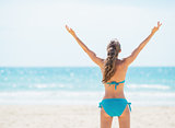 Portrait of smiling young woman rejoicing on beach. rear view