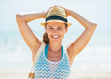 Portrait of smiling young woman in hat and with bag on beach