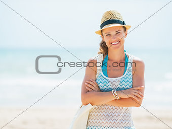 Portrait of happy young woman in hat and with bag on beach