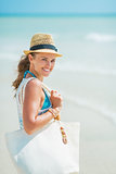 Portrait of happy young woman with hat and bag at seaside