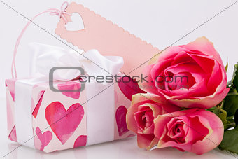 Gift box with an empty tag, next to three roses