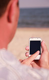 man with phone on the beach 