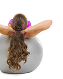 Fitness young woman making exercise on fitness ball. rear view