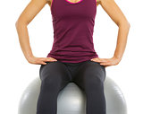 Closeup on fitness young woman sitting on fitness ball