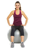 Smiling fitness young woman sitting on fitness ball