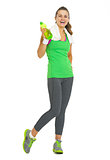 Full length portrait of smiling fitness young woman with bottle 
