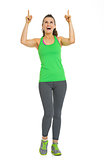 Full length portrait of fitness young woman pointing on copy spa
