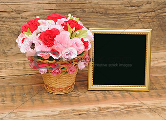 gold picture frame with paper flowers on wooden background 