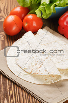 wheat tortillas with vegetables on old wooden table