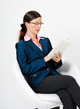 Young woman in a suit and glasses reading a book