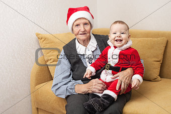 Christmas funny small baby in Santa Claus clothes with his grandmother