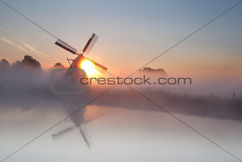 sun behind windmill and fog