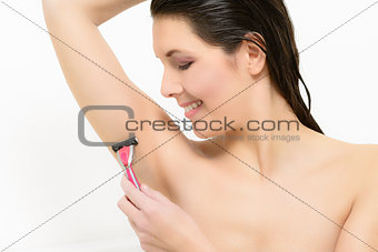 Beautiful young woman shaving her armpit