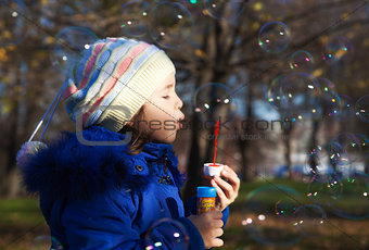 girl in blue shirt blows bubbles
