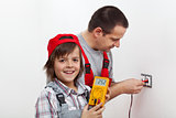 Happy boy helping his father mounting electrical wall fixtures