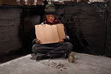 Begging homeless child sitting with a blank sign and some change