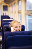 Smiling woman talking on the phone in train.