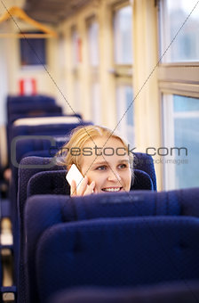 Smiling woman talking on the phone in train.