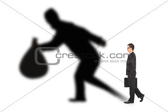 businessman walking and holding bag  with thief shadow
