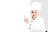 Asian smiling  young woman chef pointing  with blank board