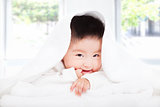 asian baby sucking  finger under  blanket or towel