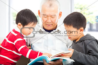 grandfather and grandchildren reading a book 