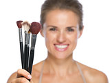 Closeup on young woman showing makeup brushes