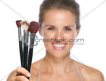 Closeup on young woman showing makeup brushes