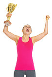 Happy fitness young woman with gold trophy cup rejoicing