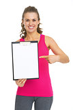 Smiling fitness young woman showing blank clipboard