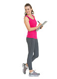 Full length portrait of smiling fitness young woman writing in c