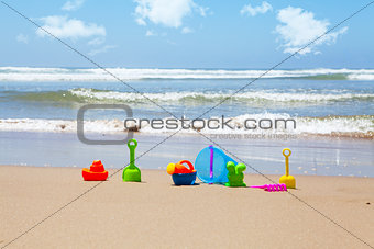 Plastic beach toys on beach with sea in background