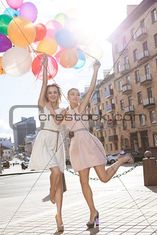 two beautiful ladys in retro outfit holding a bunch of balloons 