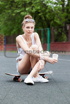 beautiful sexy lady in jeans shorts with skateboard and to-go cu