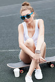 beautiful sexy lady in jeans shorts with skateboard and to-go cu