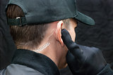 Security Guard Listens To Earpiece, Over Shoulder