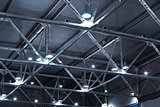 powerful lamps and metallic pipes under ceiling of industrial building
