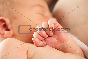 Newborn baby sleeping in mother's arm after breastfeeding