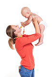 Young Caucasian woman lifting her baby son over white, boy playing with nursing necklace